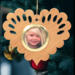Wooden heart-shaped ornament with scalloped edges and an oak grain finish, featuring a removable round gold frame that holds a photo of a smiling blonde child.