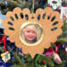 Wooden heart-shaped ornament with scalloped edges and an oak grain finish, featuring a removable round gold frame that holds a photo of a smiling blonde child.