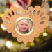 Wooden heart-shaped ornament with scalloped edges and an oak grain finish, featuring a removable round gold frame that holds a photo of a smiling blonde child.