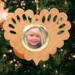 Wooden heart-shaped ornament with scalloped edges and an oak grain finish, featuring a removable round gold frame that holds a photo of a smiling blonde child.