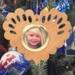 Wooden heart-shaped ornament with scalloped edges and an oak grain finish, featuring a removable round gold frame that holds a photo of a smiling blonde child.