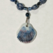 Closeup of ceramic shell pendant with blue-brown ridges attached to strand of sodalite beads and Czech crystals