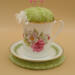This is a frontal view showing the pincushion bobbin holder sitting on the trivet. The trim on the saucer is complemented by the fabric. This is a frontal view showing the pincushion bobbin holder sitting on the trivet. The trim on the saucer is complemented by the fabric.