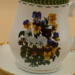 This is a closeup of the vibrant bouquet of pansies. It also shows the gold trim around the base of the cup. This is a closeup of the vibrant bouquet of pansies. It also shows the gold trim around the base of the cup.