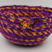 This shows the detail of the front of the basket. There is one large golden yellow flower button with 2 smaller purple ones. This shows the detail of the front of the basket. There is one large golden yellow flower button with 2 smaller purple ones.