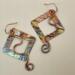 Handmade square shaped flame-colored copper earrings with swirl wire accents and handcrafted ear wires.
