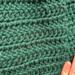 A close up of the green crochet stitches on the main scarf. The maker's fingers are in the photo for size context. A close up of the green crochet stitches on the main scarf. The maker's fingers are in the photo for size context.
