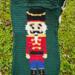 A close up of the Nutcracker pocket. He's wearing a red coat, blue pants, and black boots and hat, with yellow detailing. A close up of the Nutcracker pocket. He's wearing a red coat, blue pants, and black boots and hat, with yellow detailing.