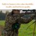 Hunter wearing camouflage gear aims rifle in a field while wearing a handmade green and black wool hunting belt bag.  Deer hunting pack. Hunter wearing camouflage gear aims rifle in a field while wearing a handmade green and black wool hunting belt bag.  Deer hunting pack.