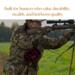 Hunter wearing camouflage gear aims rifle in a field while wearing a handmade red and black wool hunting belt bag.  Deer hunting pack. Hunter wearing camouflage gear aims rifle in a field while wearing a handmade red and black wool hunting belt bag.  Deer hunting pack.