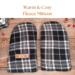Pair of warm and cozy black plaid regular sized fleece men's mittens on rustic wood background — winter regular handed mittens for men.