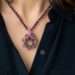 Closeup of Pink Petal Bloom necklace with beaded flower pendant on model wearing a navy blouse.