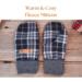 Pair of warm and cozy black and white plaid fleece regular sized women's mittens on rustic wood background — winter mittens for woman.