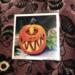 a 5 inch by 5 inch print on photo paper of a watercolor and micron pen painting of a grinning cyclopes jack o lantern. 