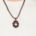 Orange Petal Bloom Necklace featuring handwoven burnt orange and black glass beads in a geometric floral pattern.