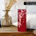 Lifestyle photo: red glitter-look hearts 20 oz skinny tumbler on a bedside table with personalized name; stainless steel.
