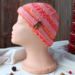 A handmade baby hat in a pink & yellow wool & acrylic yarn. Great for winter holiday gifting for newborn babies 0 to 12 months.