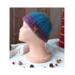 A side view of a handmade baby hat in a blue & purple wool blend yarn. Great for winter holiday gifting for newborn babies 0 to 12 months.