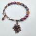 Handmade bracelet with purple beads, lavender stones, copper leaf beads, and a floral copper charm and copper pinecone charm