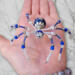 Handcrafted blue spider ornament made with glass beads, pearl like accents, and a decorative silver bead body.