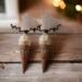 Two handmade reindeer hot cocoa cones on rustic wood with warm Christmas lights and festive holiday décor