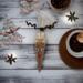 Single reindeer hot cocoa cone with mug of cocoa and Christmas decorations on rustic wood background