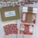 A handmade card kit to DIY 6 cards. The kit contains red scrapbook paper with a quilt design, die cut embellishments and ribbon.