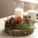Close up of handmade rustic Valentine candle centerpiece with pinecones, faux greenery, red hearts, and glass hurricane
