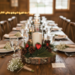 Wedding table centerpiece featuring rustic wood slice candle decor with pine greenery and red heart accents