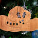 Handmade wooden Christmas tree ornament shaped like a cowboy hat, featuring a sprig of holly tucked into the hat band, hand cut holly leaf cutouts, and round berry accents.