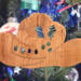 Handmade wooden Christmas tree ornament shaped like a cowboy hat, featuring a sprig of holly tucked into the hat band, hand cut holly leaf cutouts, and round berry accents.