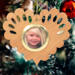 Wooden heart-shaped ornament with scalloped edges and an oak grain finish, featuring a removable round gold frame that holds a photo of a smiling blonde child.