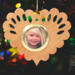 Wooden heart-shaped ornament with scalloped edges and an oak grain finish, featuring a removable round gold frame that holds a photo of a smiling blonde child.