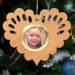 Wooden heart-shaped ornament with scalloped edges and an oak grain finish, featuring a removable round gold frame that holds a photo of a smiling blonde child.