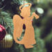 A handmade wooden Christmas ornament in the shape of a cheerful angel, featuring a halo, wings, and a raised arm ringing a bell, hand-cut from solid hardwood and finished with clear shellac.
