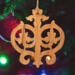 Intricate Victorian-style fretwork Christmas tree ornament handcrafted from natural hardwood with visible wood grain, showcasing symmetrical curls, loops, and ornate cut-out designs.