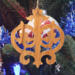 Intricate Victorian-style fretwork Christmas tree ornament handcrafted from natural hardwood with visible wood grain, showcasing symmetrical curls, loops, and ornate cut-out designs.