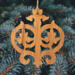 Intricate Victorian-style fretwork Christmas tree ornament handcrafted from natural hardwood with visible wood grain, showcasing symmetrical curls, loops, and ornate cut-out designs.