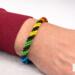 Handmade Rainbow Helix Kumihimo bracelet worn on wrist, showing scale and fit of the spiral beaded design on light concrete