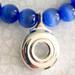 Close up of blue glass beads, shilver open hole flute key pendant.