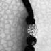 Three elements of necklace: cord, black and white beads.