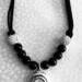 Full view of black necklace with open hole pendant flute key.