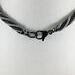 Close up image of black stainless steel lobster claw clasp on black and grey beaded necklace