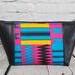 Pink blue and orange geometric print makeup bag with black faux leather accents, silver top zipper.